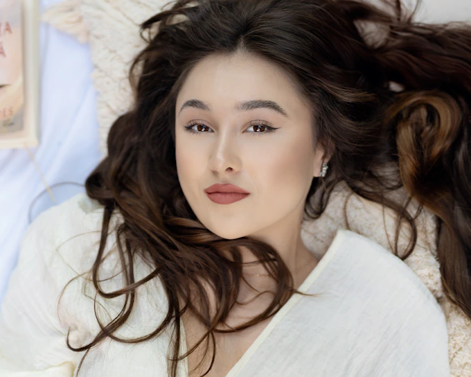 a woman laying on top of a bed next to a book