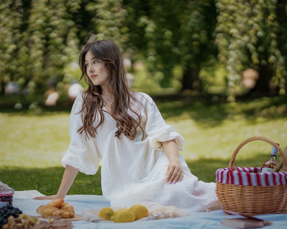 a woman sitting on a blanket in a park