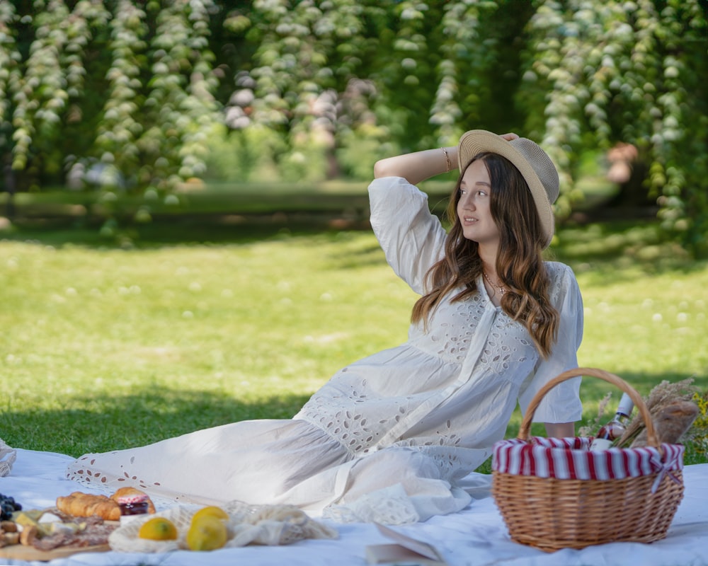 a woman sitting on a blanket with a picnic basket