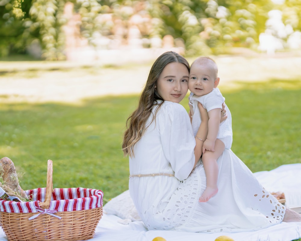 a woman in a white dress holding a baby