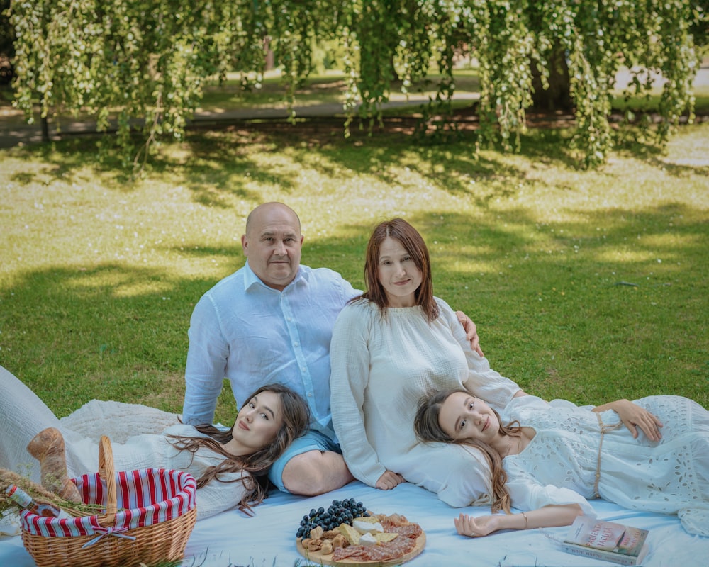 a family sitting on a blanket in a park