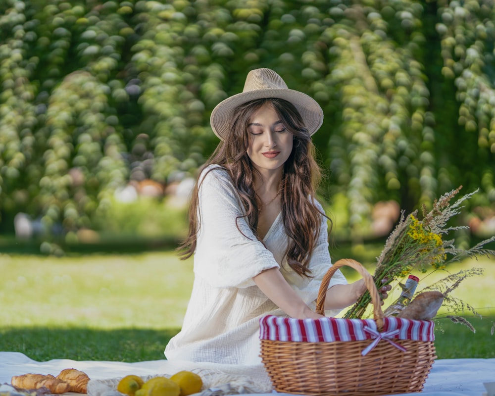 a woman sitting on a blanket holding a basket