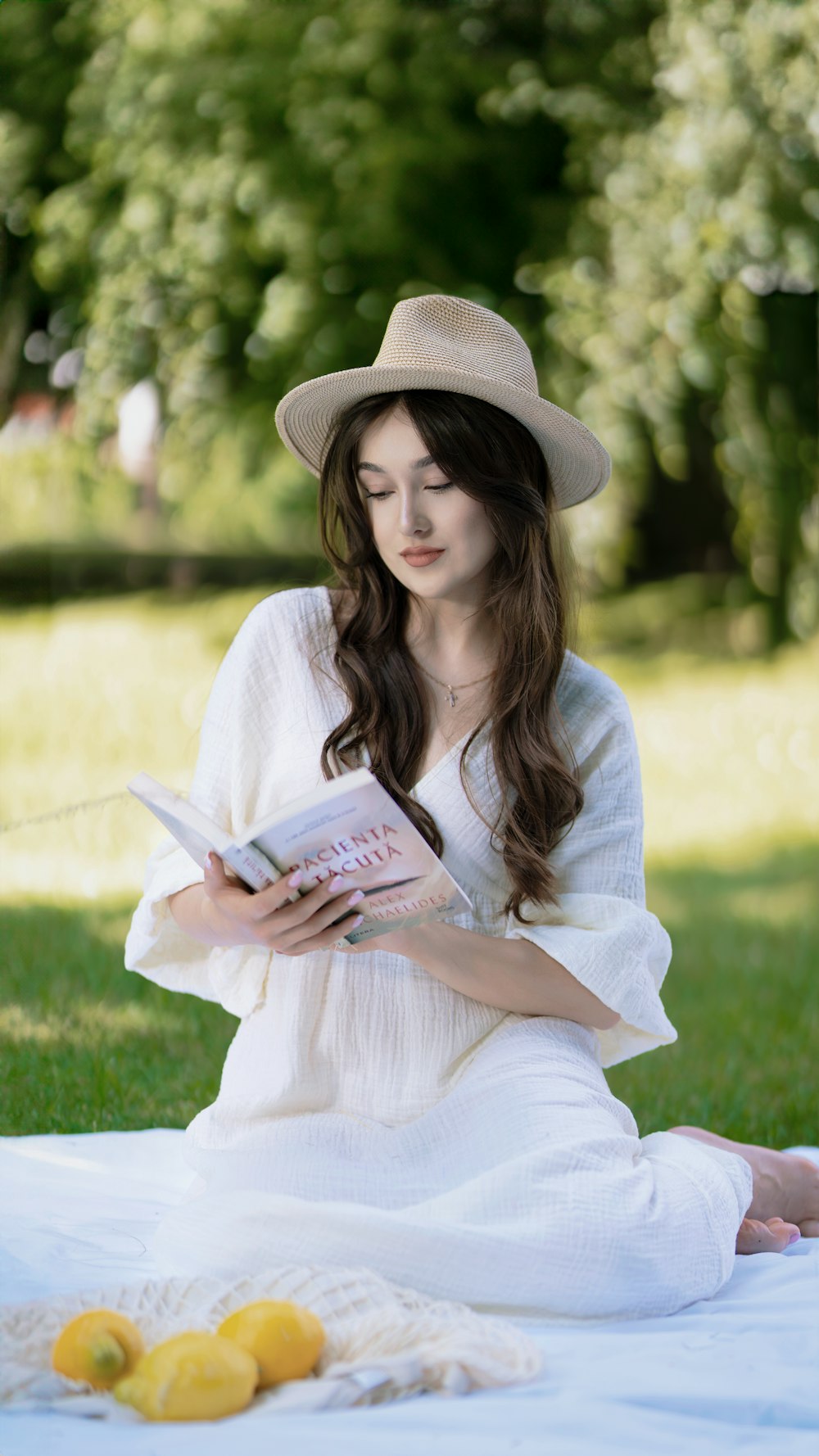 a woman sitting on a blanket reading a book