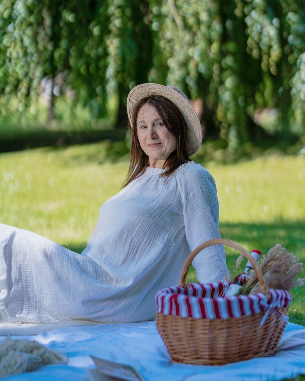 a woman sitting on a blanket with a picnic basket