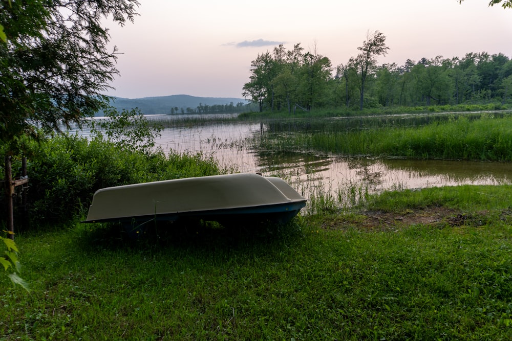 a small boat sitting on top of a lush green field