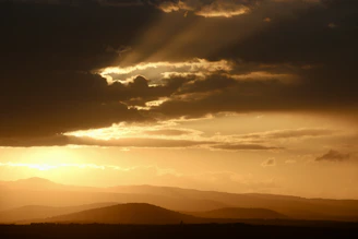 A serene sunrise breaking through dark clouds over a quiet landscape, symbolizing hope after crisis.