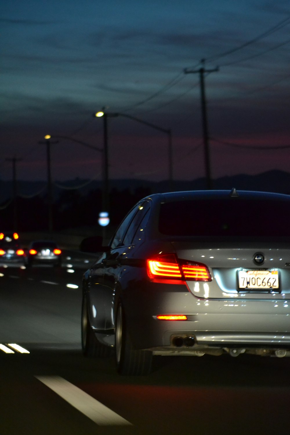 a silver car driving down a street at night