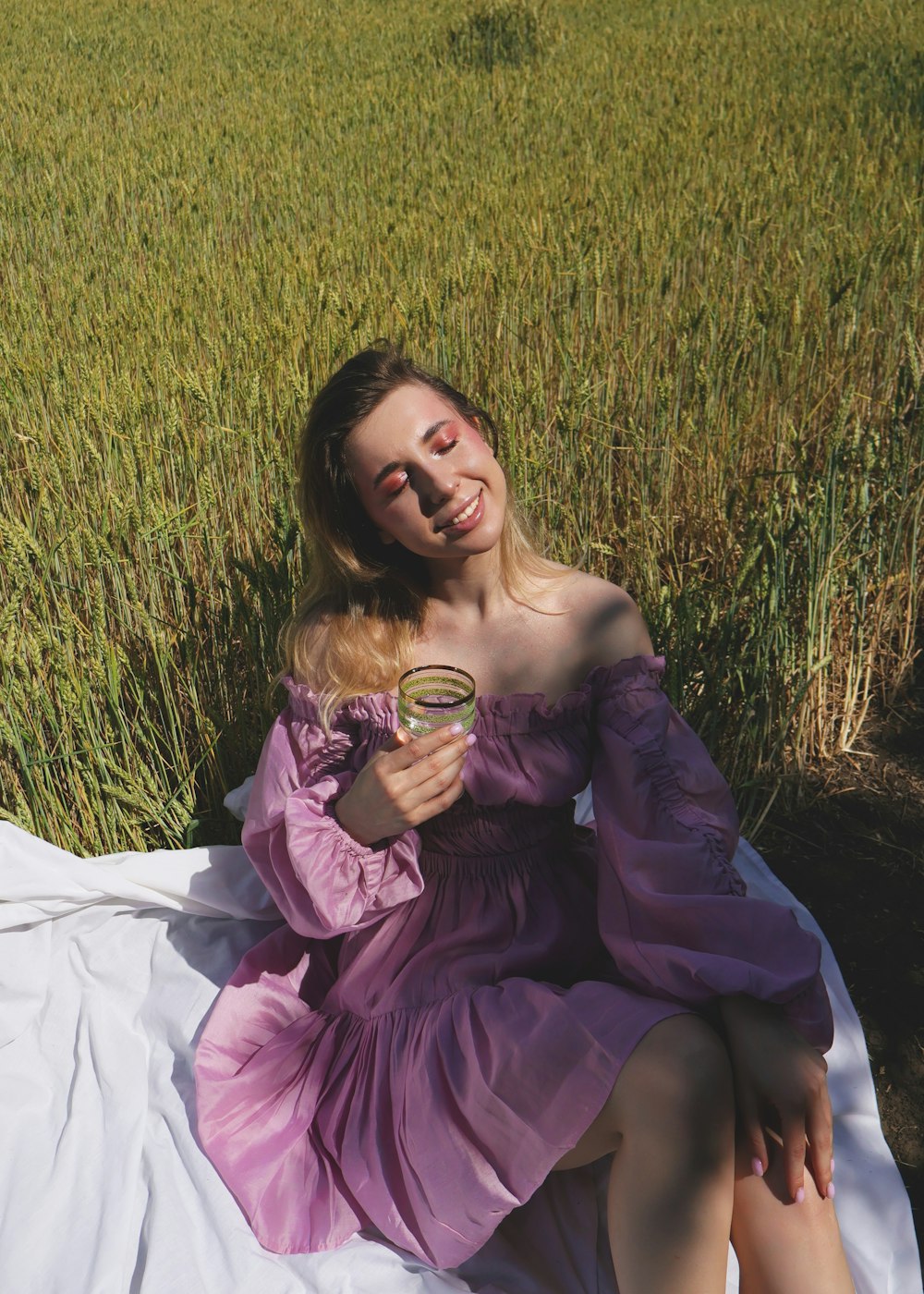 a woman in a purple dress sitting in a field