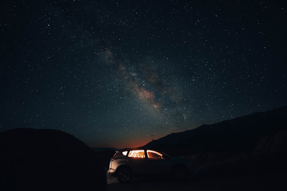 a car parked in the middle of a field under a night sky filled with stars