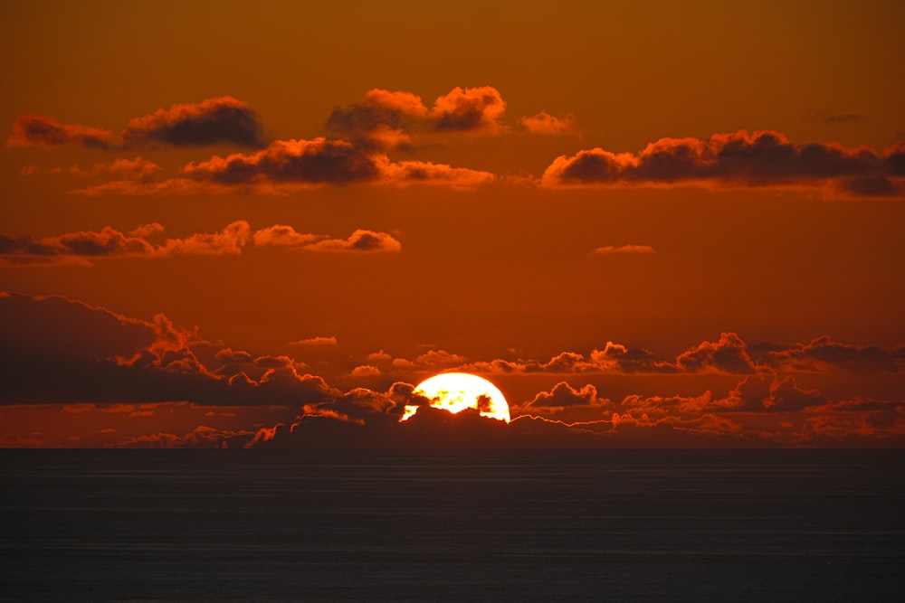 太陽は雲のある海に沈んでいます
