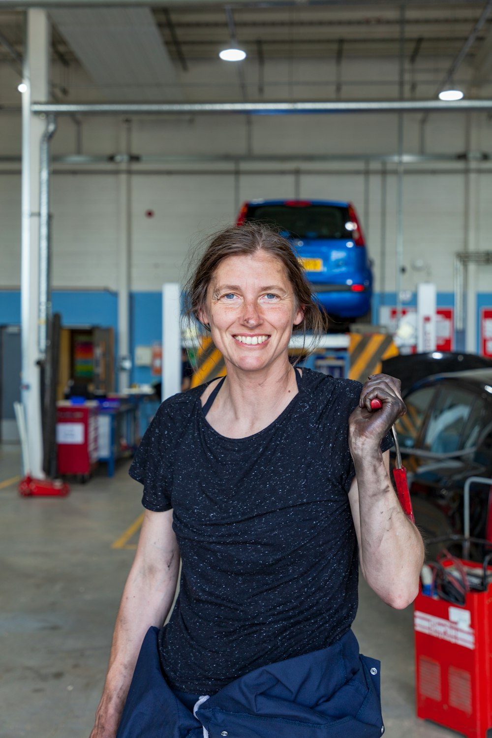 a woman holding a wrench in a garage