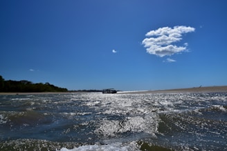 A scenic view of a boat cruising near the sandy bank of Crôa do Goré with clear blue waters.