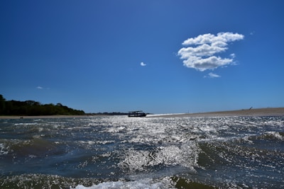 A scenic view of a boat cruising near the sandy bank of Crôa do Goré with clear blue waters.