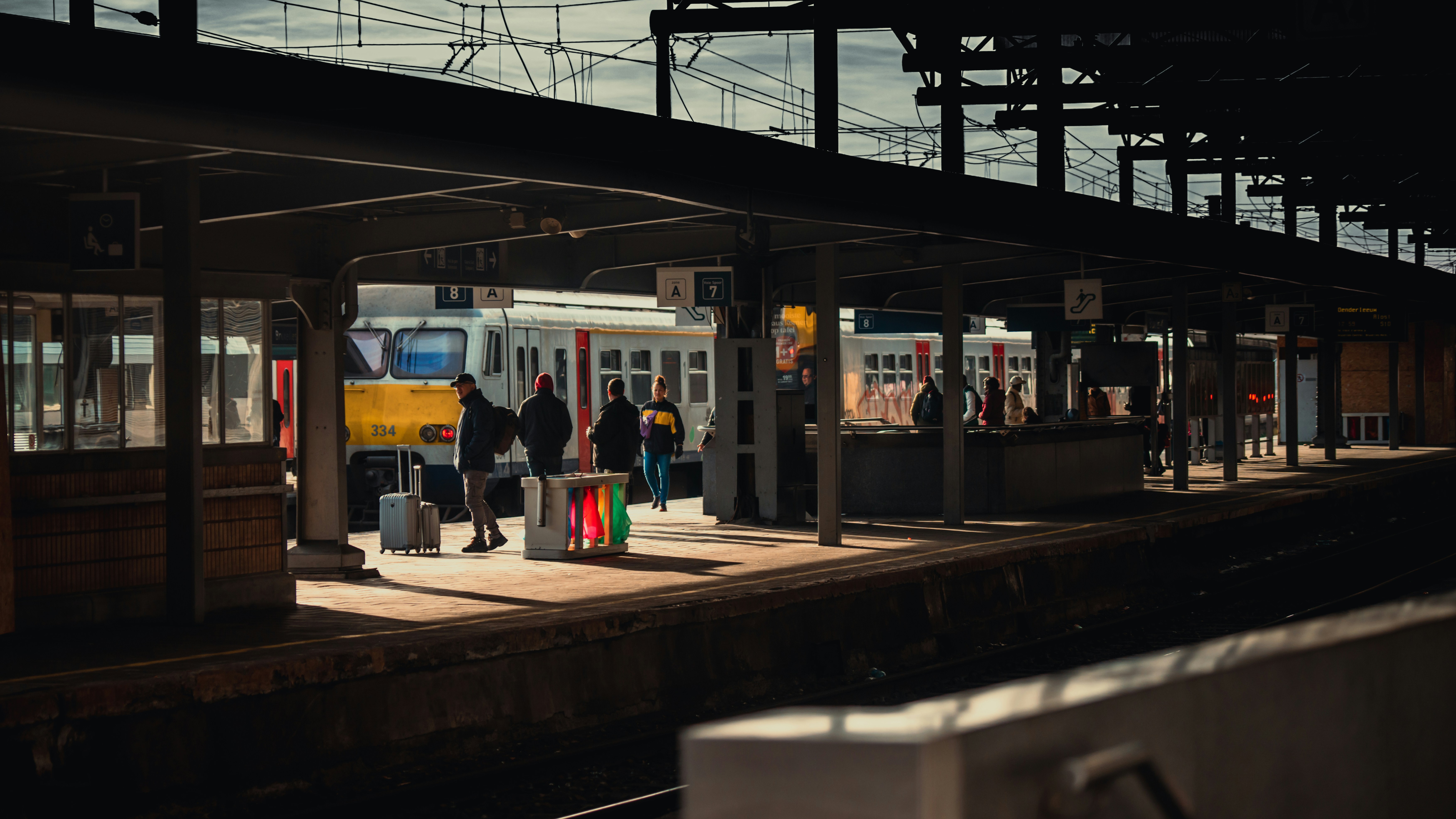 a group of people standing at a train station, 