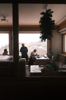 A group of happy travelers sharing tea at a cozy mountain lodge surrounded by pine trees.