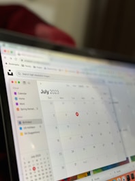 A computer screen displaying a digital calendar for July 2023. The screen shows a sidebar with calendar categories such as Home, Work, and Birthdays. The days of the month are displayed in a grid format, and the calendar is part of an application interface with browser icons visible at the top.