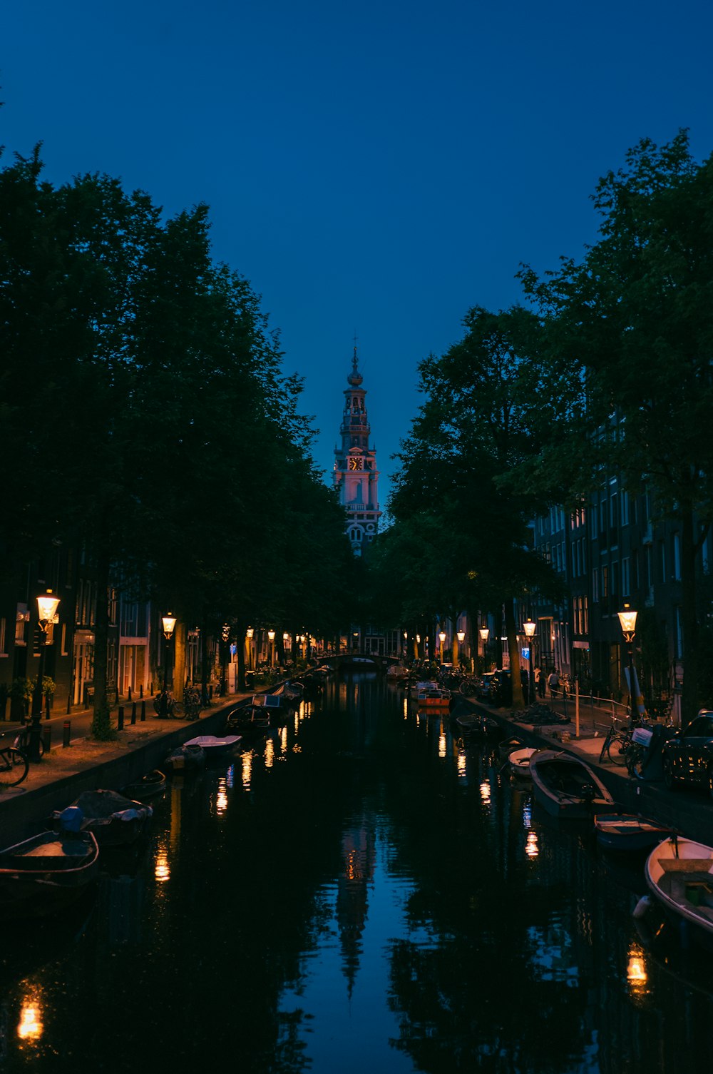 a canal with many boats on it and a clock tower in the background