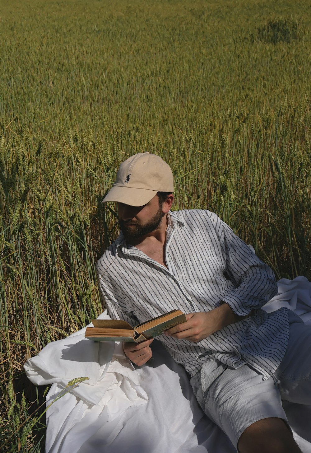 a man sitting in a field reading a book