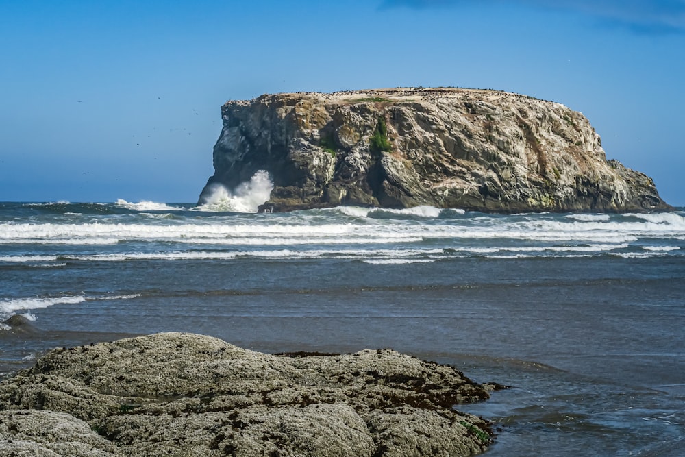 a large rock sitting on top of a beach next to the ocean