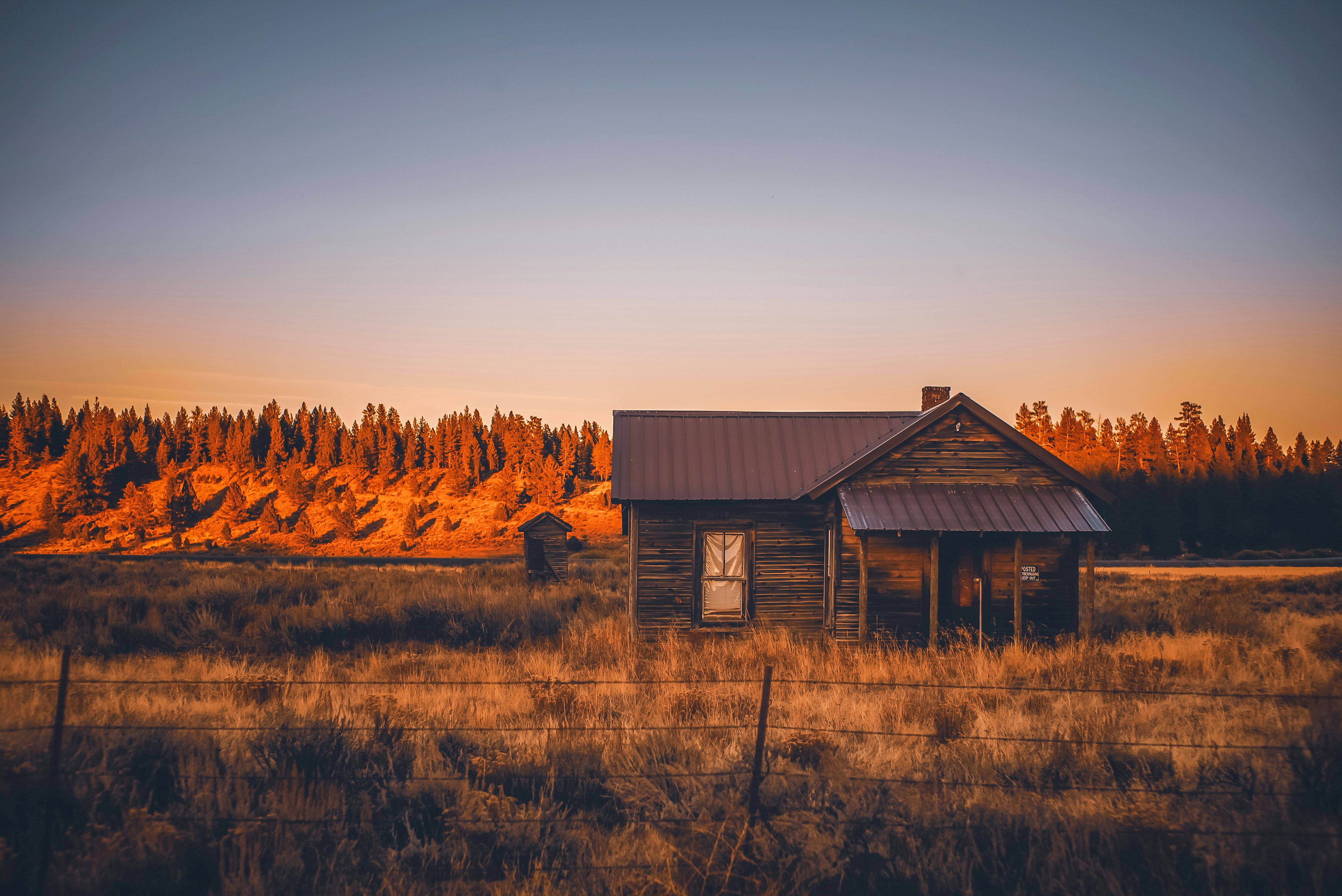 a small cabin in a field with a fence around it