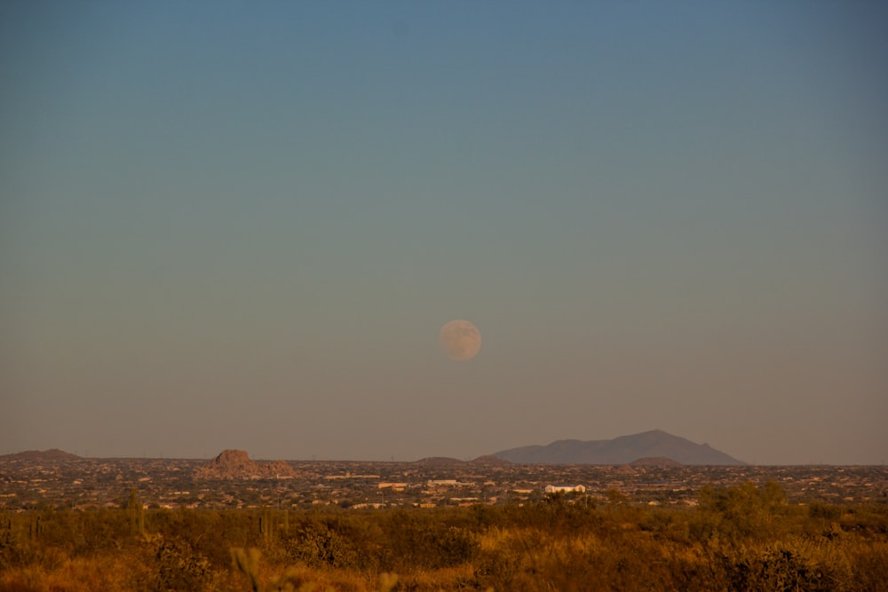a full moon is seen over a desert landscape