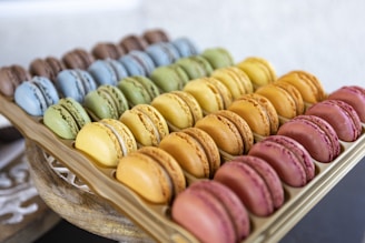 An assortment of colorful macarons arranged neatly on a rustic wooden tray.