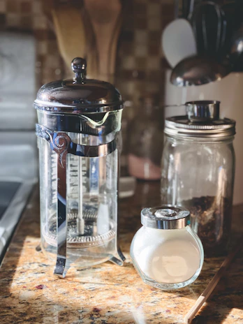 A modern kitchen counter with a sleek French press and a bag of Quimbayan Coffee.