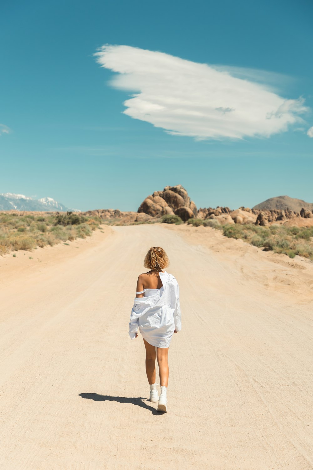 a woman walking down a dirt road in the desert