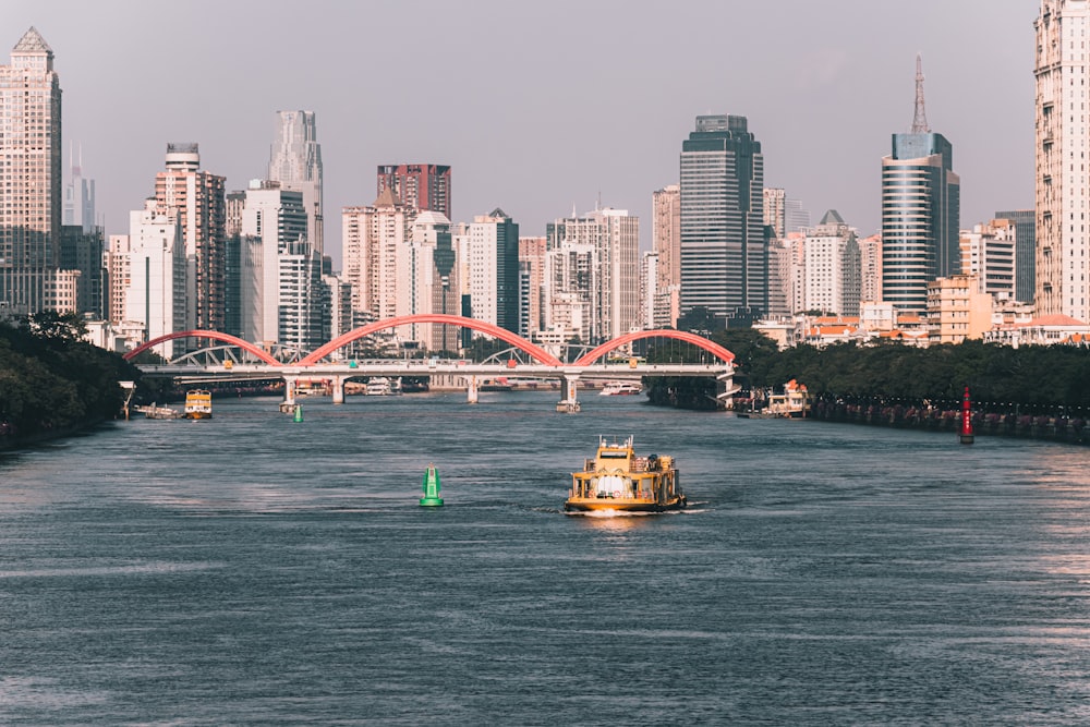 a yellow boat traveling down a river next to tall buildings
