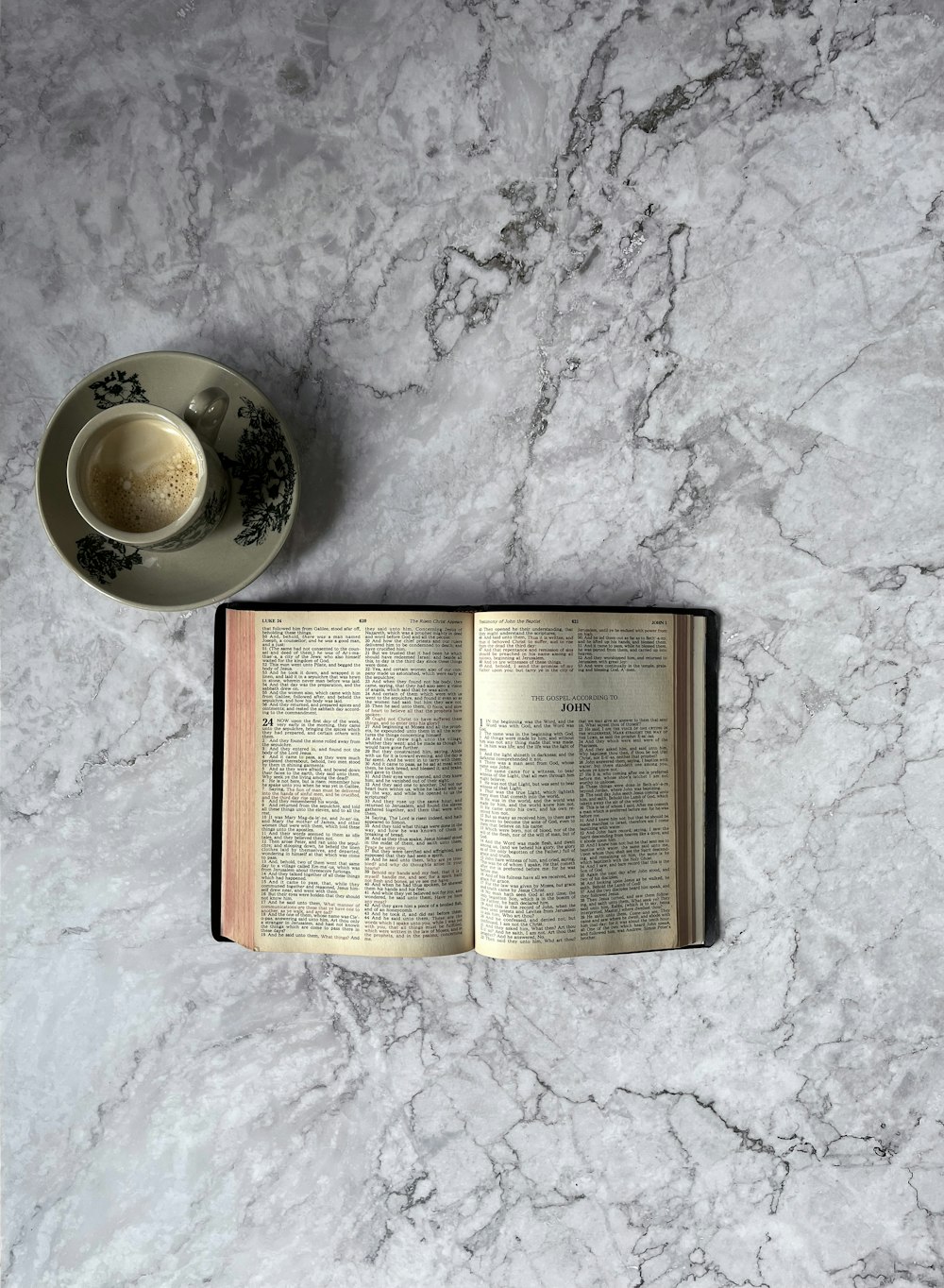 an open book and a cup of coffee on a marble table