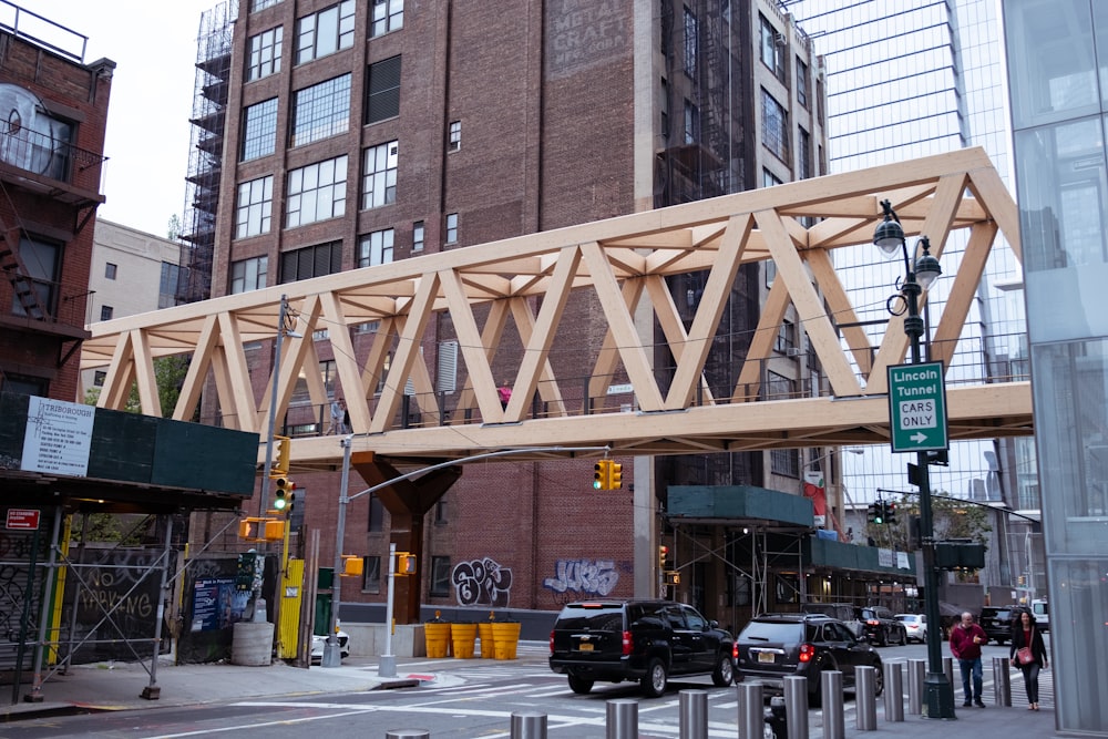 a wooden bridge over a city street next to tall buildings