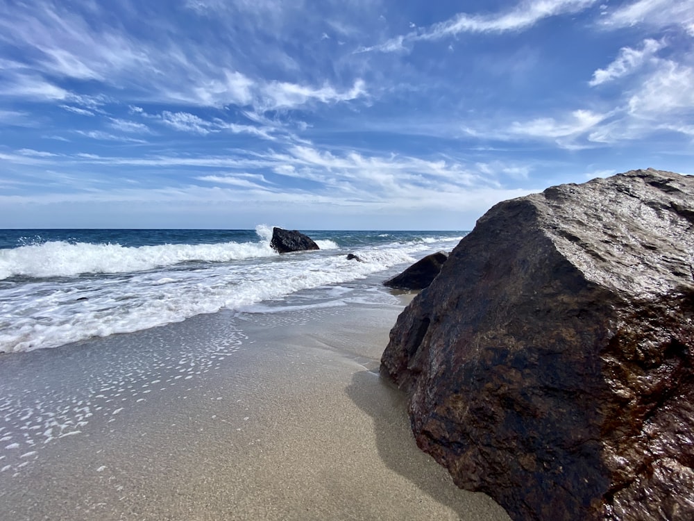 una grande roccia seduta sulla cima di una spiaggia sabbiosa