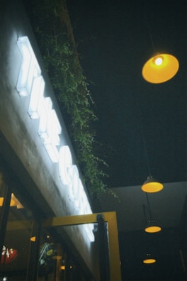 The exterior of dronecafe at dusk, with neon drone signage glowing against the evening sky