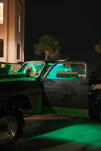 A strong neon green tow truck from Fuerza Verde assisting a car on a busy New Jersey street at night.