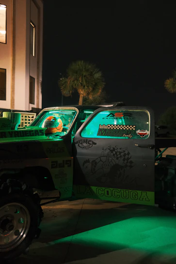 A strong neon green tow truck from Fuerza Verde assisting a car on a busy New Jersey street at night.