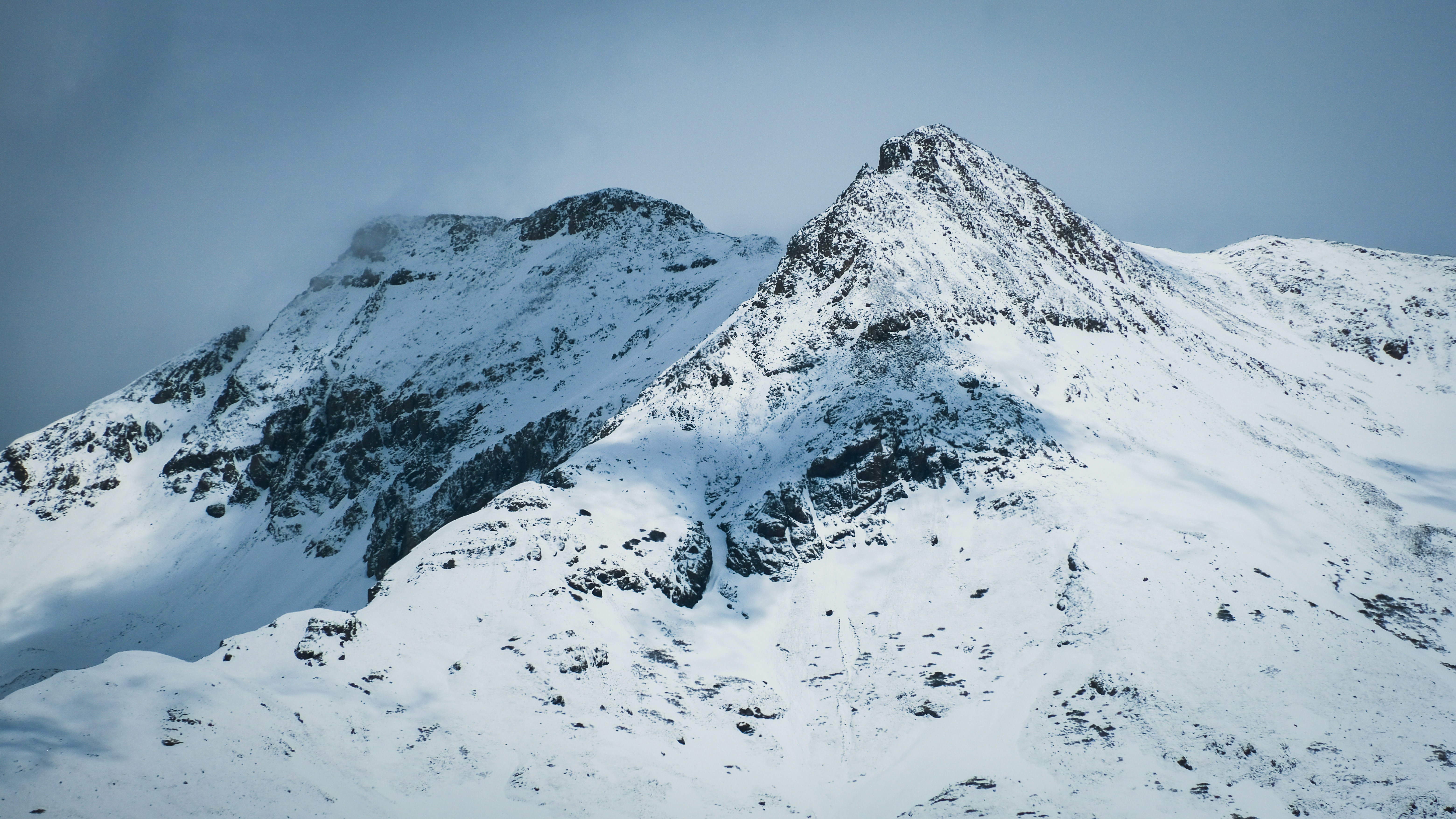 a mountain covered in snow with a sky background