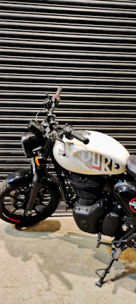 A sleek Royal Enfield motorcycle parked in front of the Majestik Rides dealership on a sunny day.