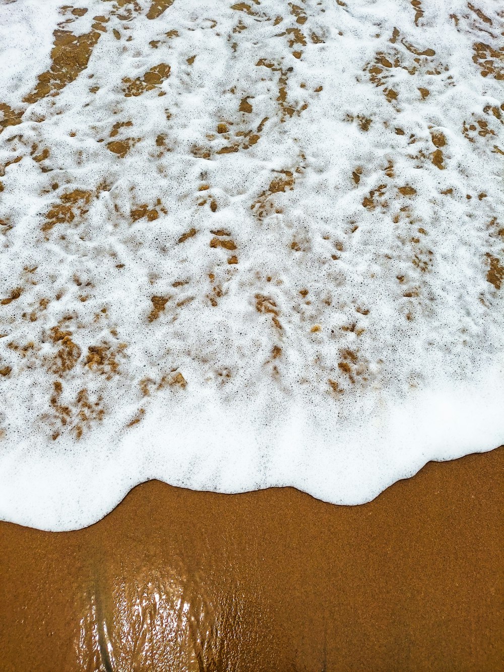 a close up of a wave on a sandy beach