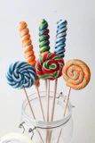 Brightly colored candy sticks and lollipops in a jar