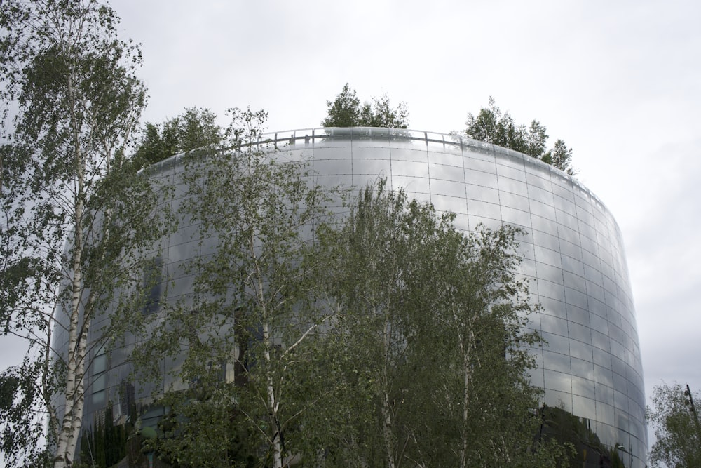 a large round building surrounded by trees on a cloudy day