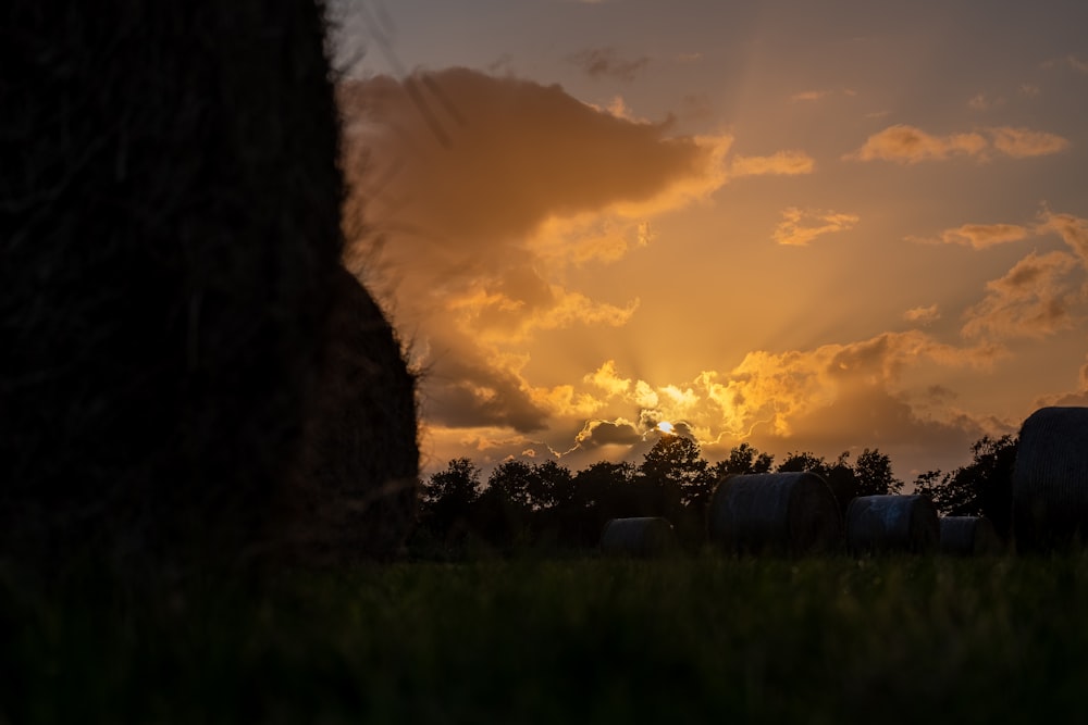 the sun is setting over hay bales in a field