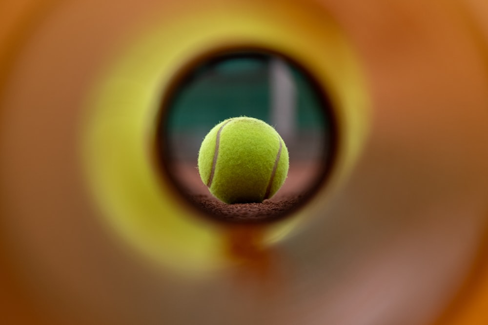 a tennis ball is seen through a hole in a wall
