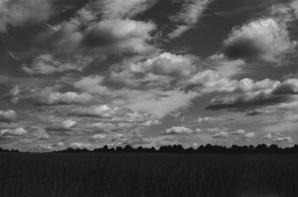 a black and white photo of clouds over a field