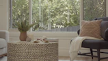 A round coffee table styled with a stack of books and a small potted plant.