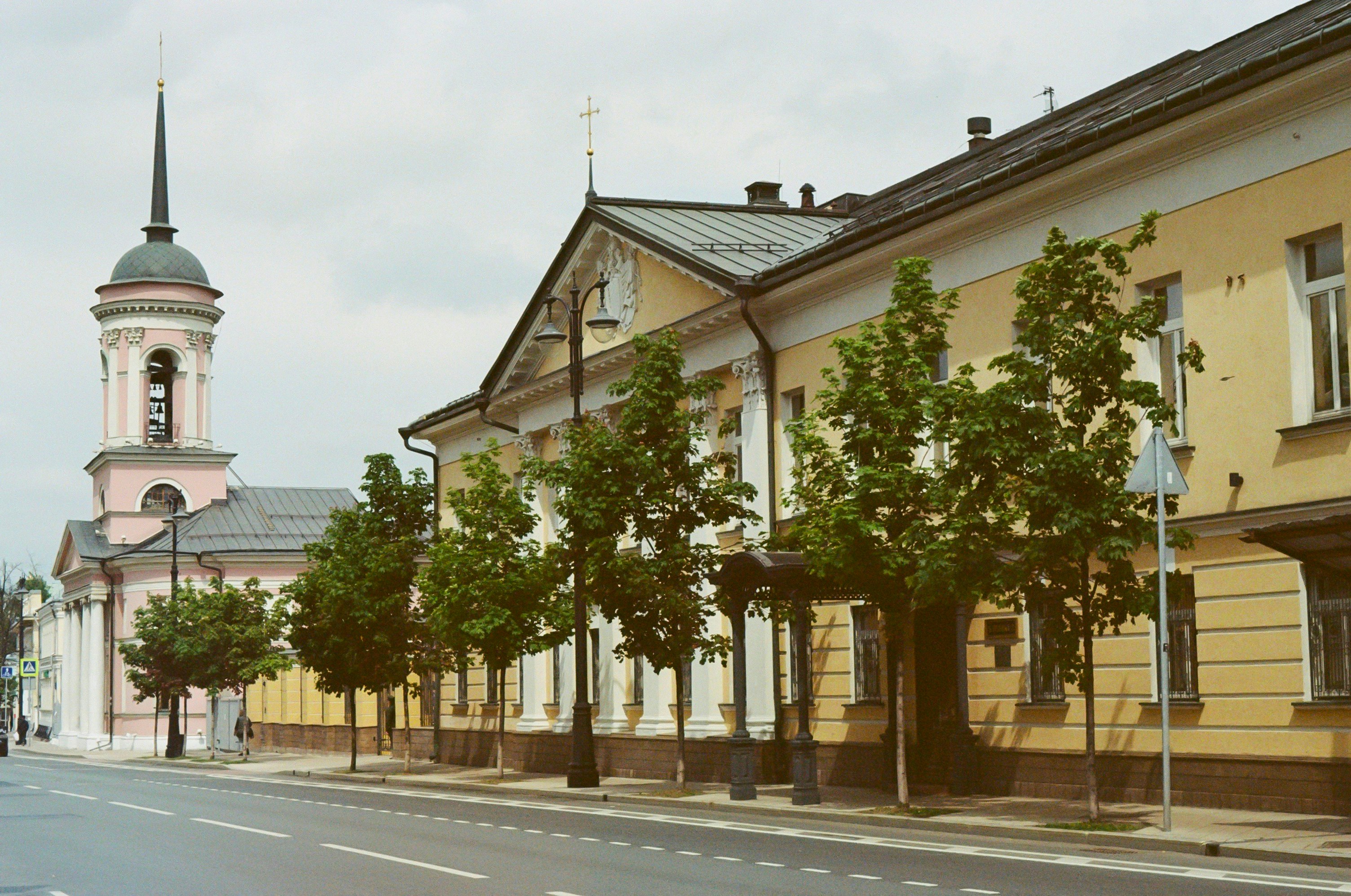 a street lined with tall buildings with a clock tower in the background