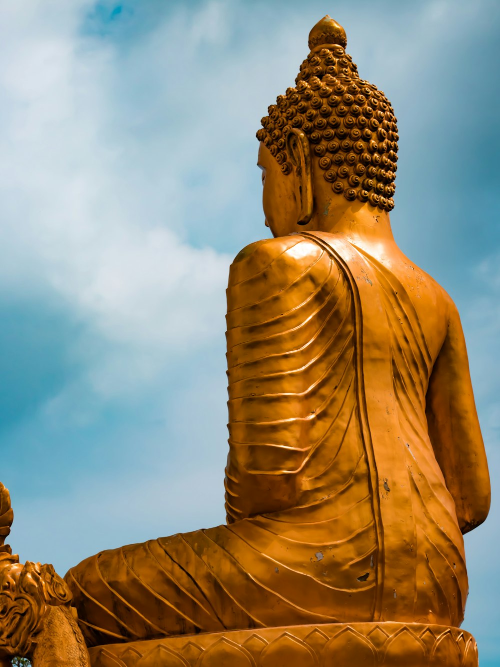 a golden buddha statue sitting in the middle of a field