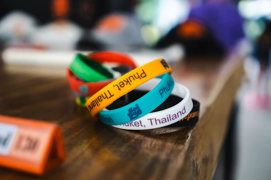 Close-up of colorful festival wristbands and tickets on a wooden table with warm evening light