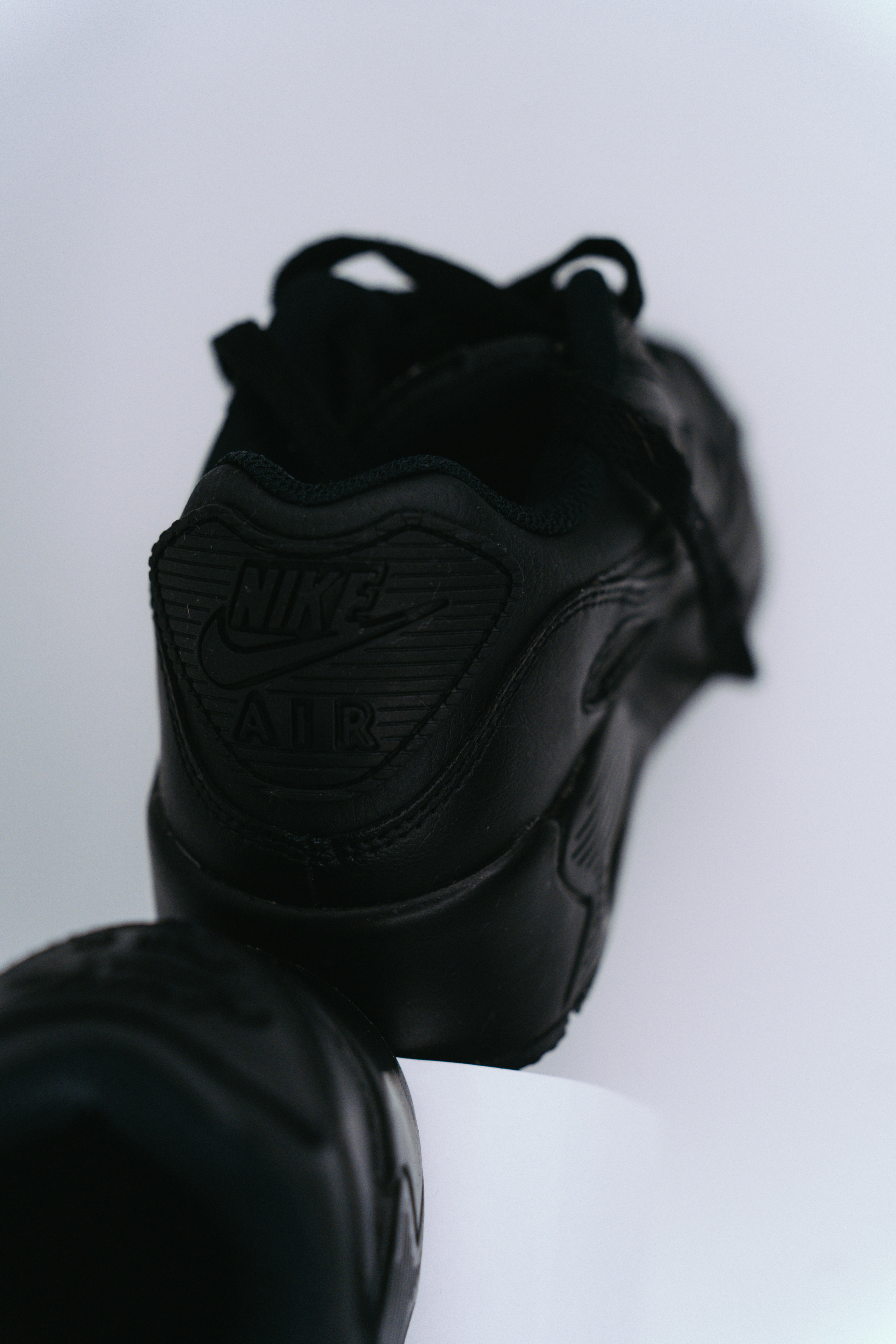 a pair of black sneakers sitting on top of a white table