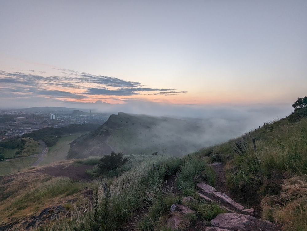 a foggy mountain with a trail going up the side of it