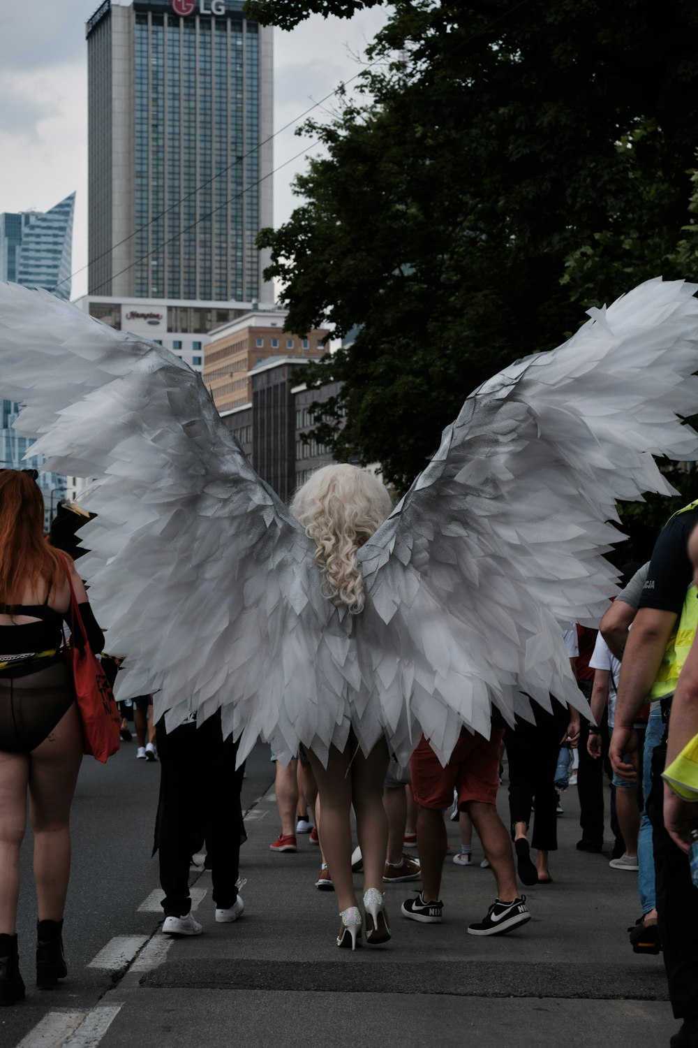 a woman with white wings walking down a street